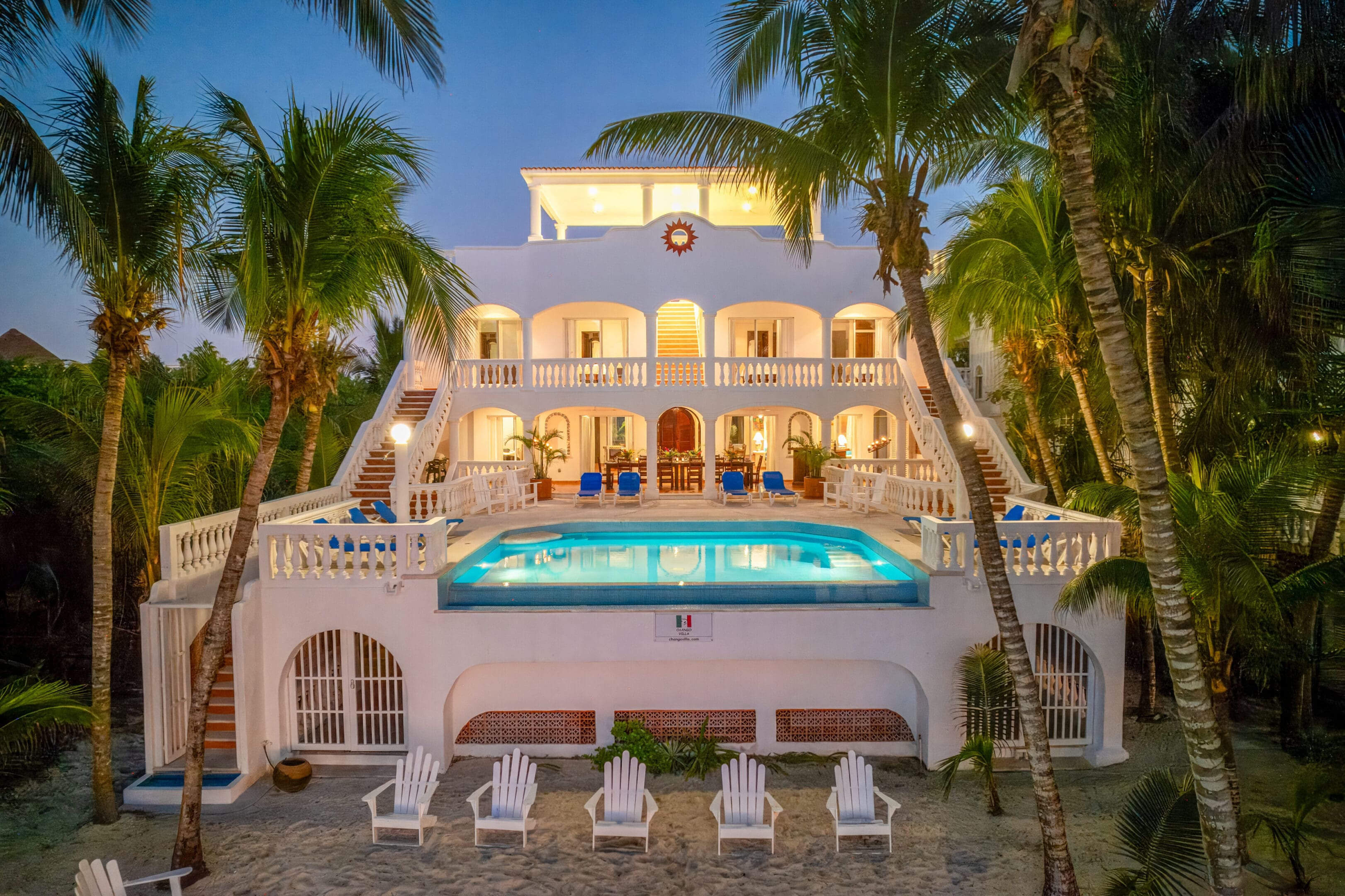 A large white house with palm trees and a pool.